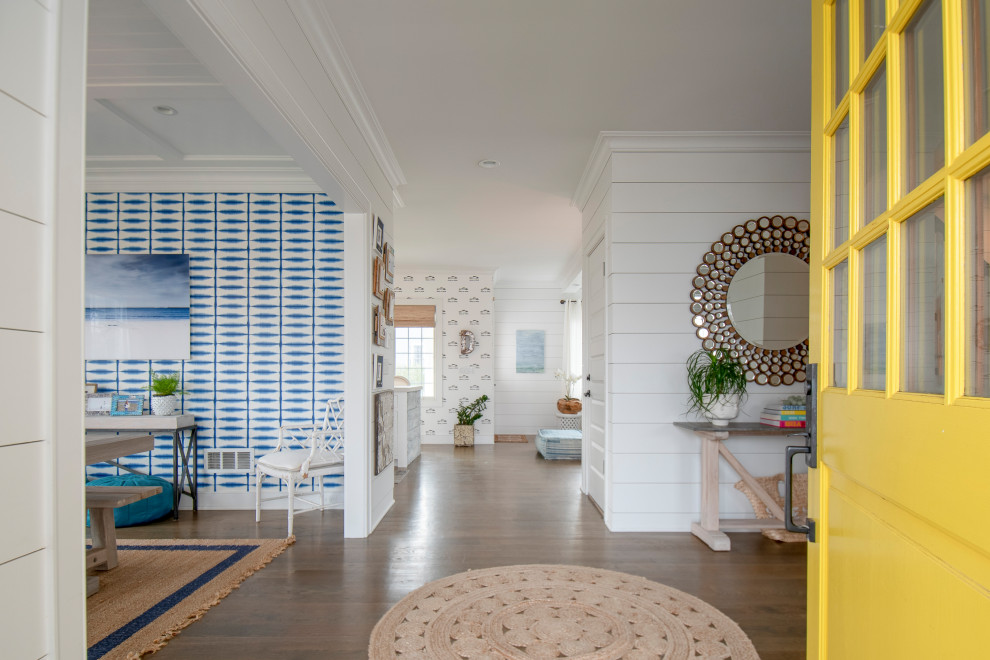 This is an example of a large beach style entryway in Other with white walls, light hardwood floors, a single front door, a yellow front door, brown floor and planked wall panelling.
