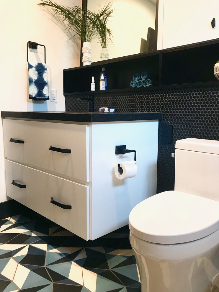 Inspiration for a mid-sized transitional kids bathroom in Orange County with flat-panel cabinets, white cabinets, an alcove tub, a shower/bathtub combo, a one-piece toilet, black tile, cement tile, white walls, concrete floors, an undermount sink, granite benchtops, blue floor, a sliding shower screen and black benchtops.
