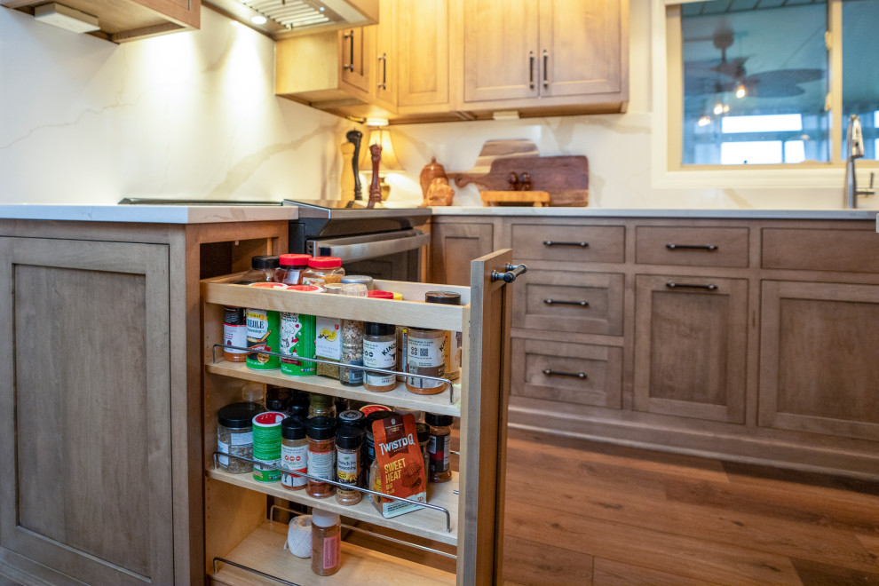 Large transitional l-shaped medium tone wood floor and brown floor eat-in kitchen photo with a single-bowl sink, shaker cabinets, medium tone wood cabinets, quartz countertops, white backsplash, quartz backsplash, stainless steel appliances, an island and white countertops