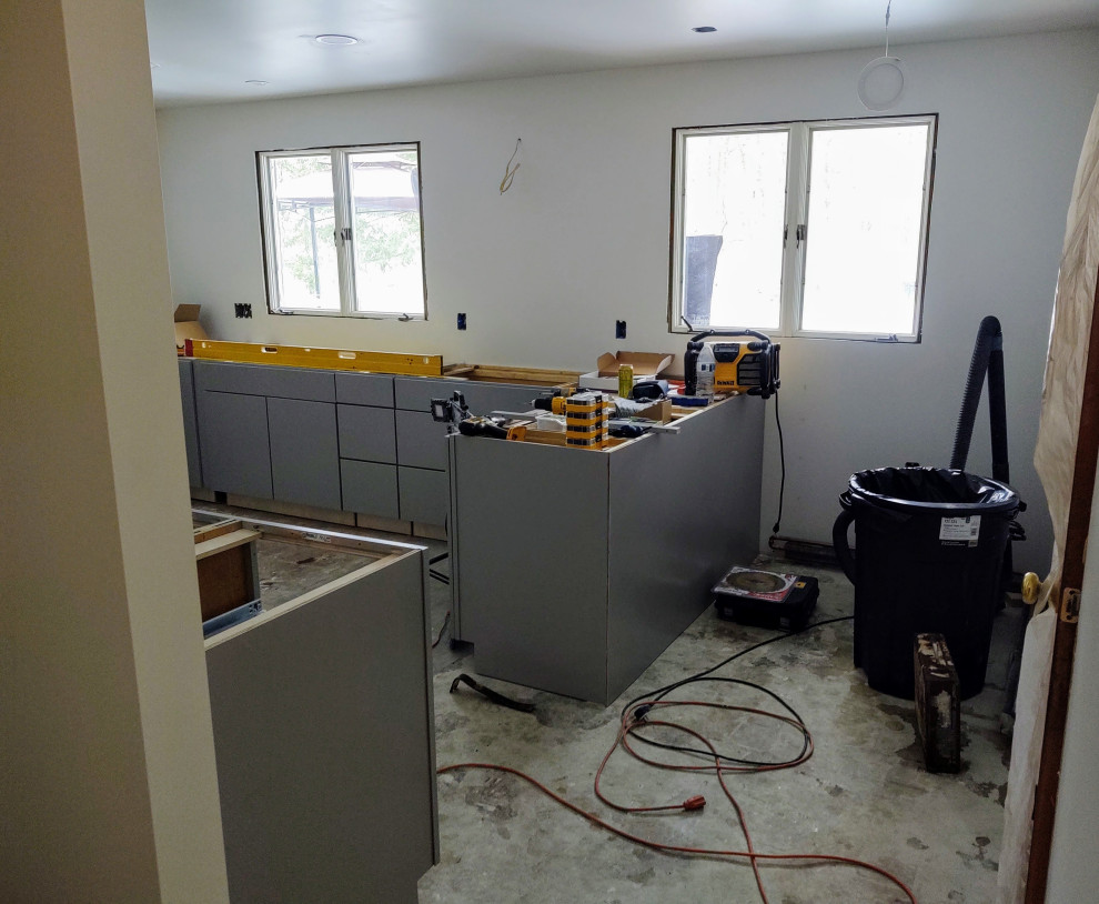 Enclosed kitchen - mid-sized enclosed kitchen idea with flat-panel cabinets, gray cabinets and a peninsula