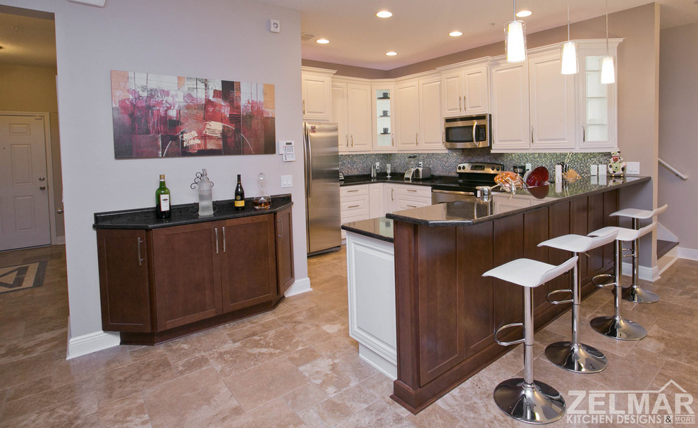 Photo of a mid-sized traditional u-shaped eat-in kitchen in Orlando with raised-panel cabinets, white cabinets, quartz benchtops, multi-coloured splashback, glass tile splashback and a peninsula.