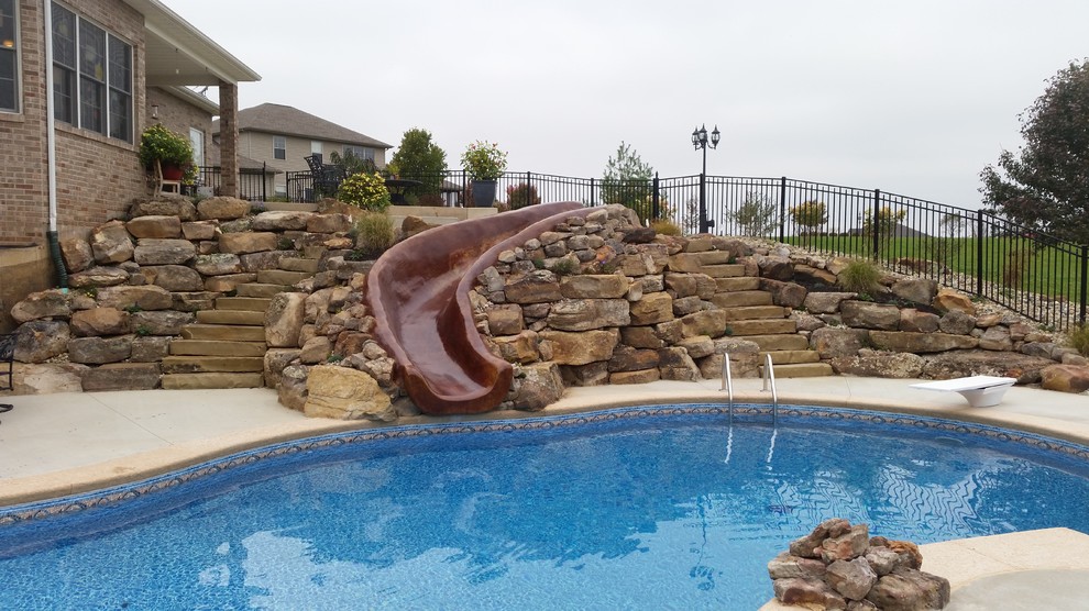 Mid-sized country backyard custom-shaped pool in St Louis with a water slide and concrete slab.
