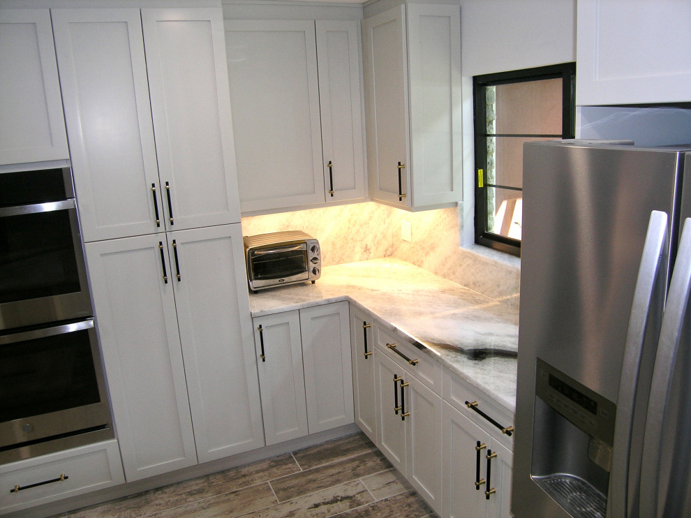 Lantlig inredning av ett stort grå grått kök, med en enkel diskho, skåp i shakerstil, vita skåp, granitbänkskiva, grått stänkskydd, rostfria vitvaror, klinkergolv i porslin, en köksö och grått golv