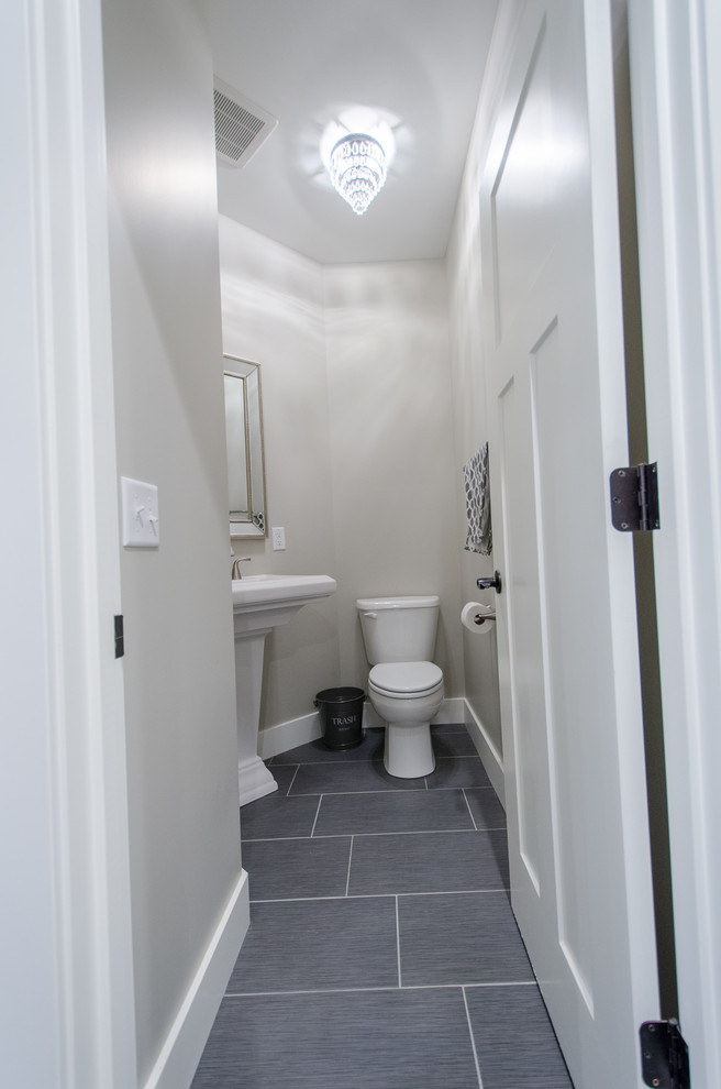 Example of a small transitional vinyl floor powder room design with a two-piece toilet, beige walls and a pedestal sink
