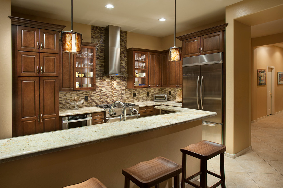 Mid-sized transitional single-wall travertine floor eat-in kitchen photo in Phoenix with beaded inset cabinets, medium tone wood cabinets, solid surface countertops, beige backsplash, glass tile backsplash, stainless steel appliances and an island