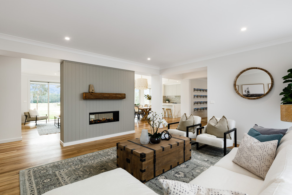 Photo of a mid-sized open concept living room in Wollongong with a two-sided fireplace, brown floor and panelled walls.