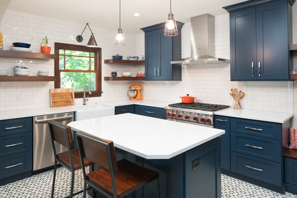 Photo of a small eclectic l-shaped eat-in kitchen in Seattle with a farmhouse sink, raised-panel cabinets, blue cabinets, quartzite benchtops, white splashback, ceramic splashback, stainless steel appliances, cement tiles, with island and black floor.