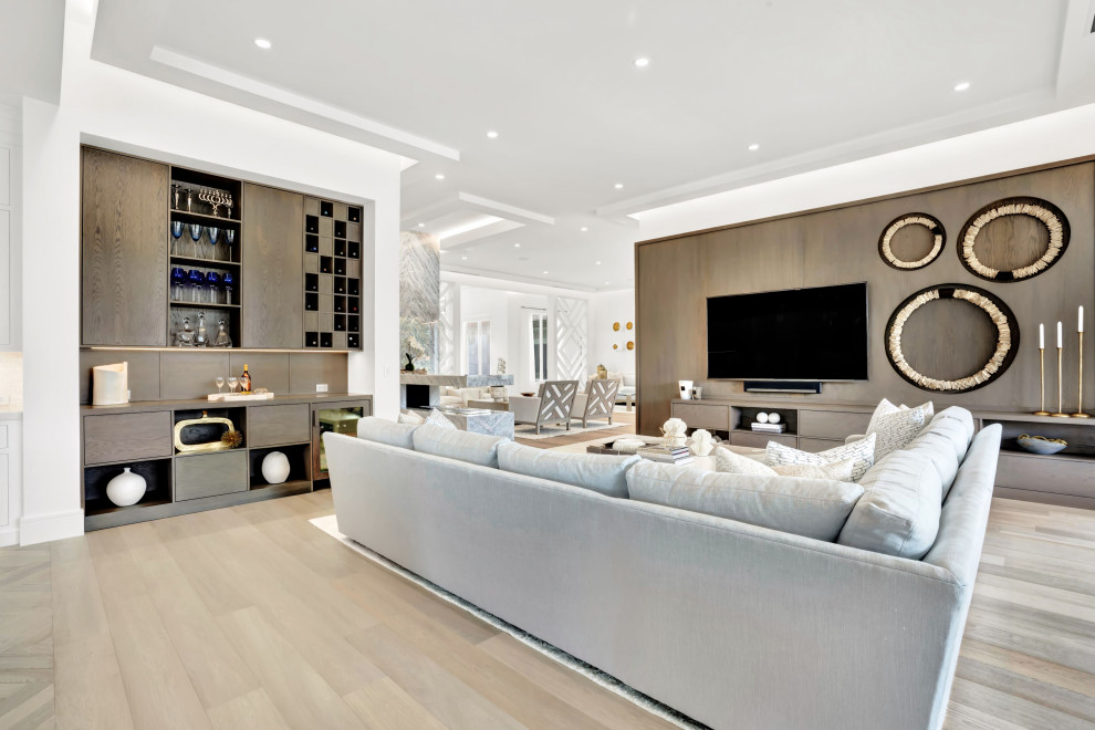 This is an example of a large contemporary open concept family room in Miami with white walls, medium hardwood floors, a hanging fireplace, a stone fireplace surround, a built-in media wall, beige floor and coffered.