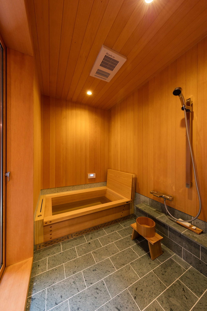 Photo of an asian bathroom in Osaka with a curbless shower, gray tile, brown walls, a japanese tub, wood and wood walls.