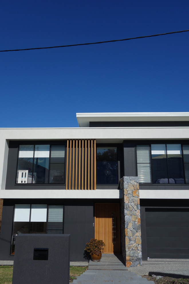 This is an example of a large modern two-storey black house exterior in Wollongong with a flat roof and a metal roof.