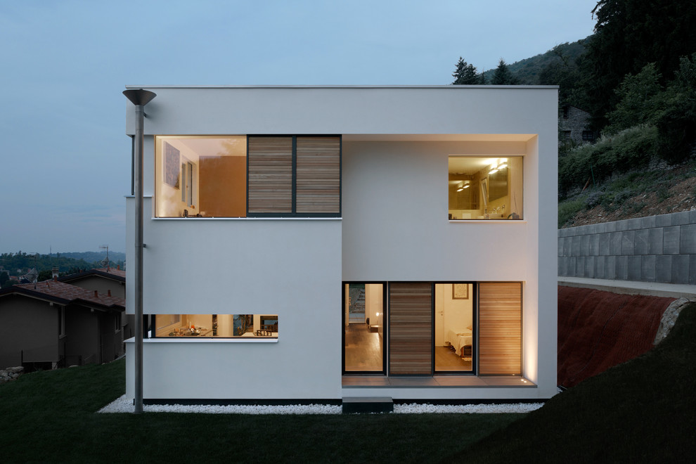 This is an example of a contemporary two-storey white exterior in Other with a flat roof.