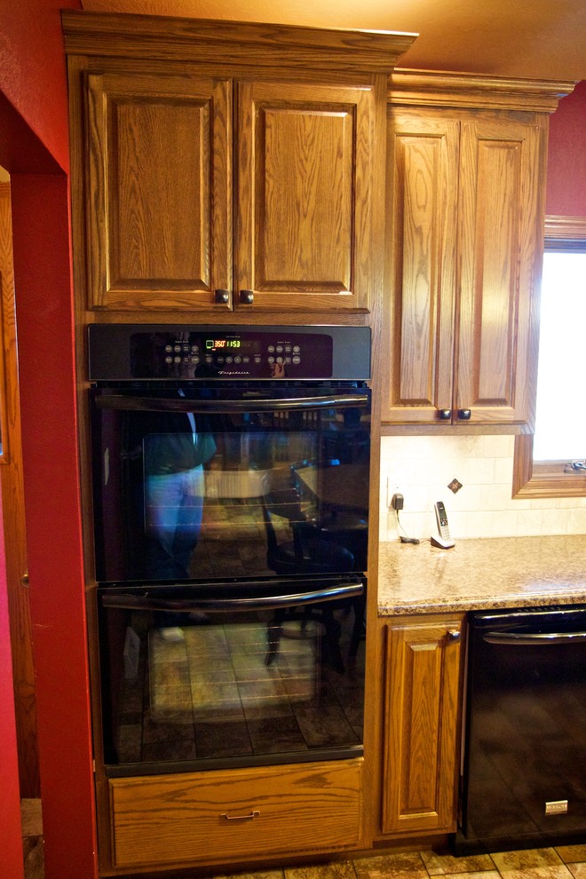 Inspiration for a mid-sized l-shaped linoleum floor open concept kitchen remodel with an undermount sink, raised-panel cabinets, medium tone wood cabinets, laminate countertops, beige backsplash, stone tile backsplash, black appliances and an island