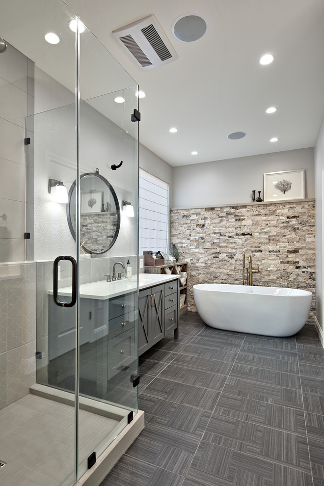 Photo of a mid-sized transitional master bathroom in Austin with furniture-like cabinets, grey cabinets, a freestanding tub, a corner shower, brown tile, ceramic tile, white walls, ceramic floors, an undermount sink and engineered quartz benchtops.