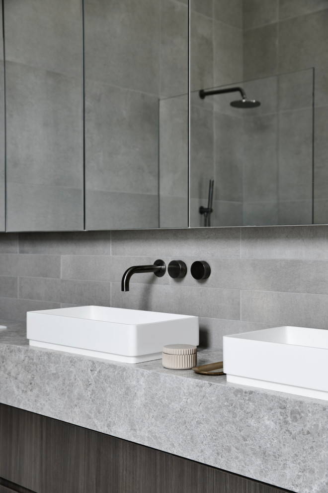 Contemporary master bathroom in Melbourne with grey cabinets, a freestanding tub, an open shower, a wall-mount toilet, gray tile, stone tile, grey walls, a vessel sink, marble benchtops, grey floor, grey benchtops, a double vanity and a floating vanity.