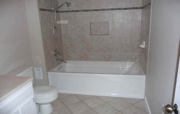 Mid-sized traditional 3/4 bathroom in DC Metro with flat-panel cabinets, white cabinets, an alcove tub, a shower/bathtub combo, a two-piece toilet, beige tile, ceramic tile, beige walls, ceramic floors and an integrated sink.