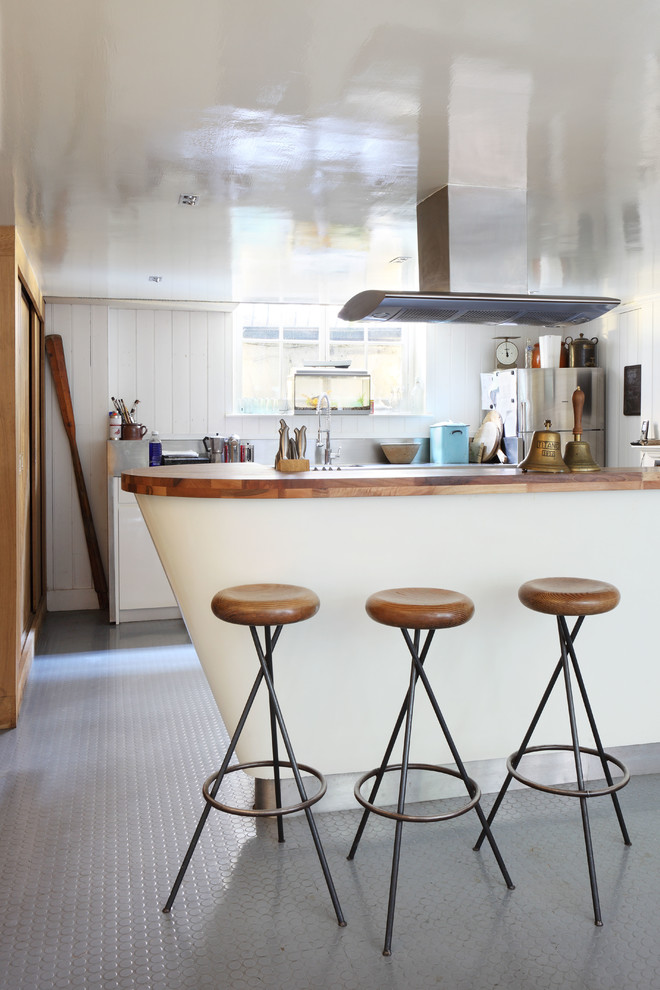 Photo of an eclectic galley kitchen in London with wood benchtops and stainless steel appliances.