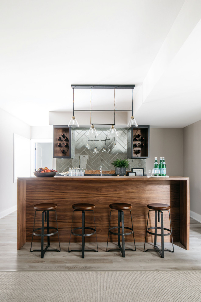 Large traditional galley wet bar in Chicago with an undermount sink, shaker cabinets, medium wood cabinets, mirror splashback, light hardwood floors, grey floor and grey benchtop.