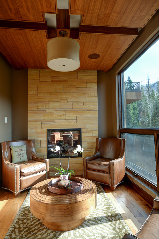 Photo of a mid-sized contemporary formal open concept living room in Denver with beige walls, light hardwood floors, a two-sided fireplace, a tile fireplace surround and no tv.