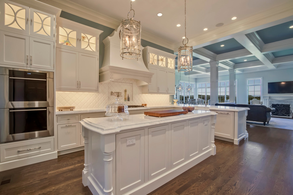 Open concept kitchen - huge transitional medium tone wood floor open concept kitchen idea with a farmhouse sink, beaded inset cabinets, white cabinets, marble countertops, white backsplash, ceramic backsplash, paneled appliances and an island
