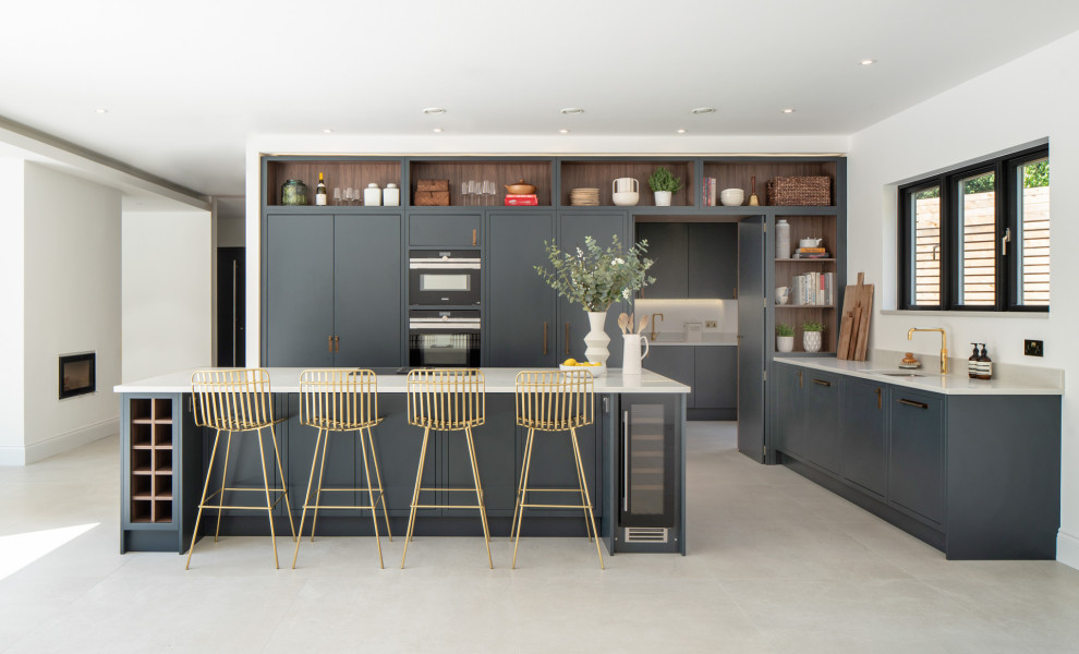 Inspiration for a contemporary l-shaped kitchen in London with an undermount sink, flat-panel cabinets, grey cabinets, black appliances, with island, grey floor and grey benchtop.
