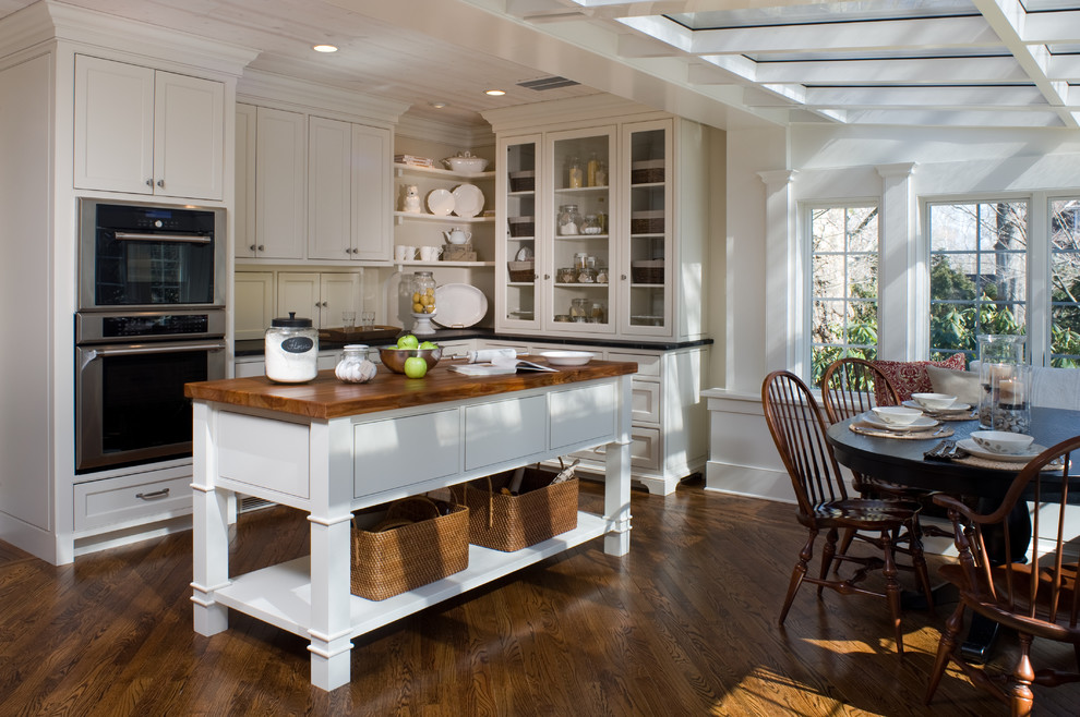 Inspiration for a traditional eat-in kitchen in Philadelphia with glass-front cabinets, stainless steel appliances and wood benchtops.