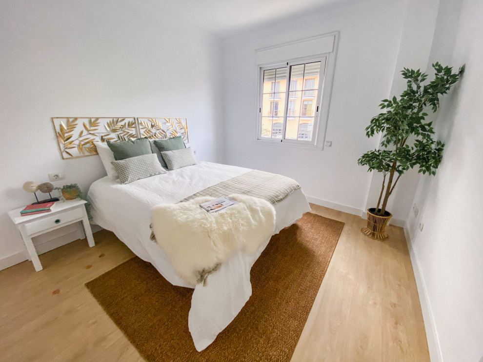 Modelo de dormitorio principal grande con paredes blancas, suelo de madera en tonos medios y suelo beige