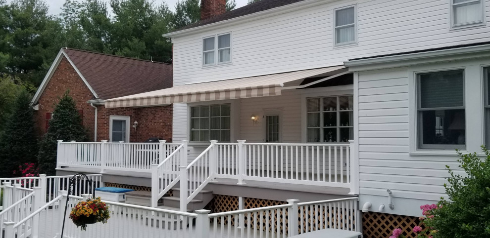 This is an example of an expansive arts and crafts backyard deck in Philadelphia with an awning.