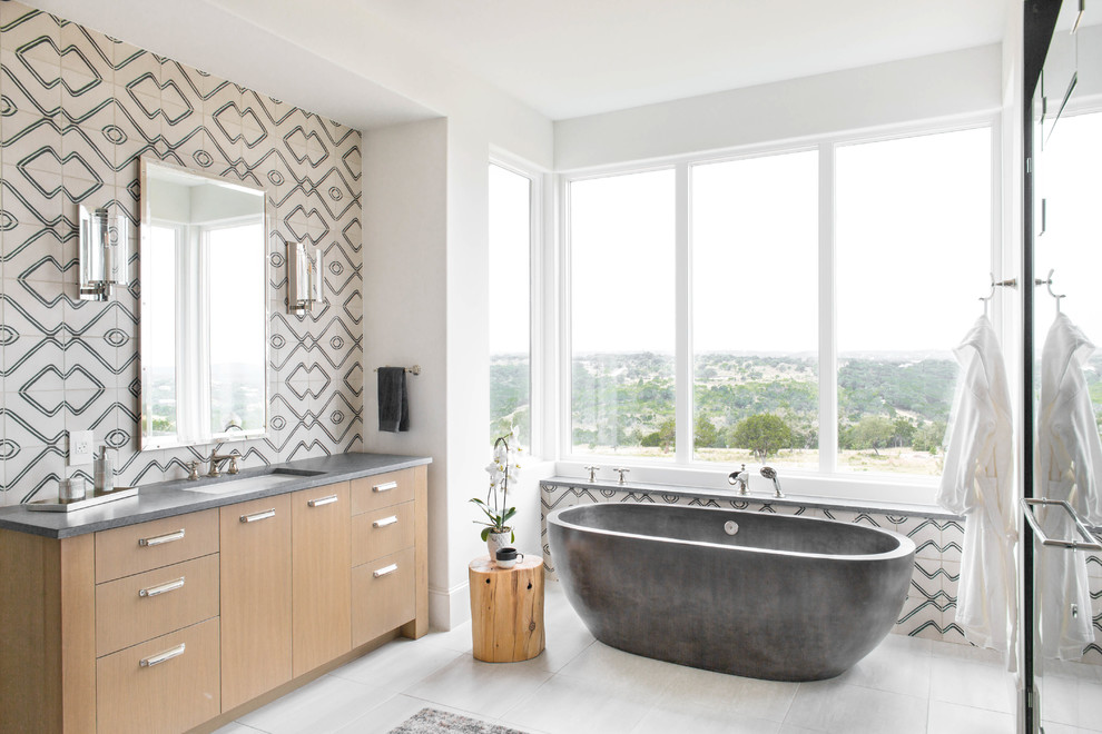 This is an example of a contemporary master bathroom in Austin with flat-panel cabinets, light wood cabinets, a freestanding tub, black and white tile, multi-coloured tile, an undermount sink, concrete benchtops and white floor.
