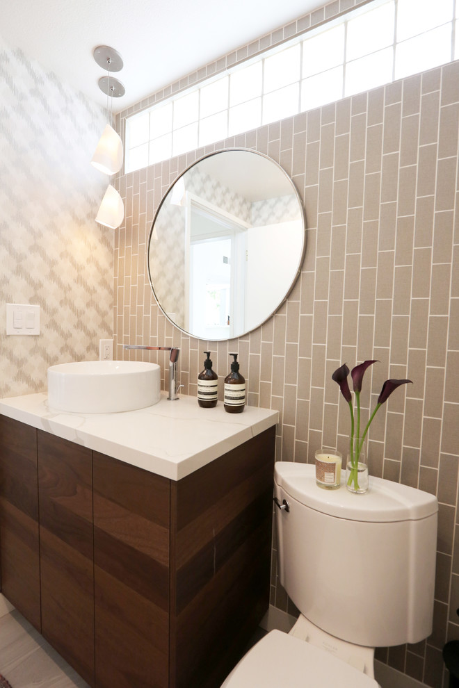 Photo of a small modern 3/4 bathroom in Los Angeles with flat-panel cabinets, dark wood cabinets, a one-piece toilet, gray tile, ceramic tile, multi-coloured walls, ceramic floors, a vessel sink, engineered quartz benchtops, grey floor and white benchtops.