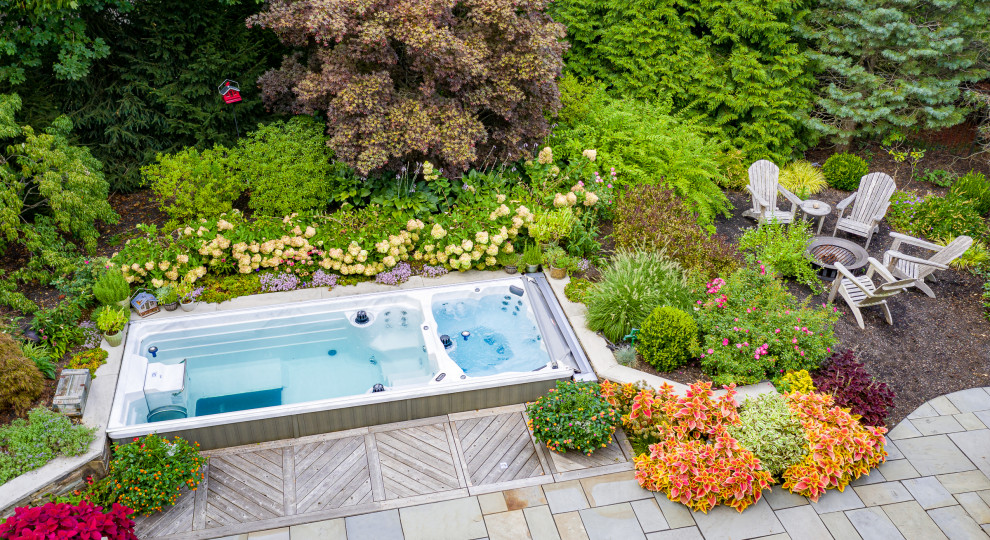 This is an example of a small classic back rectangular swimming pool in New York with with pool landscaping and natural stone paving.