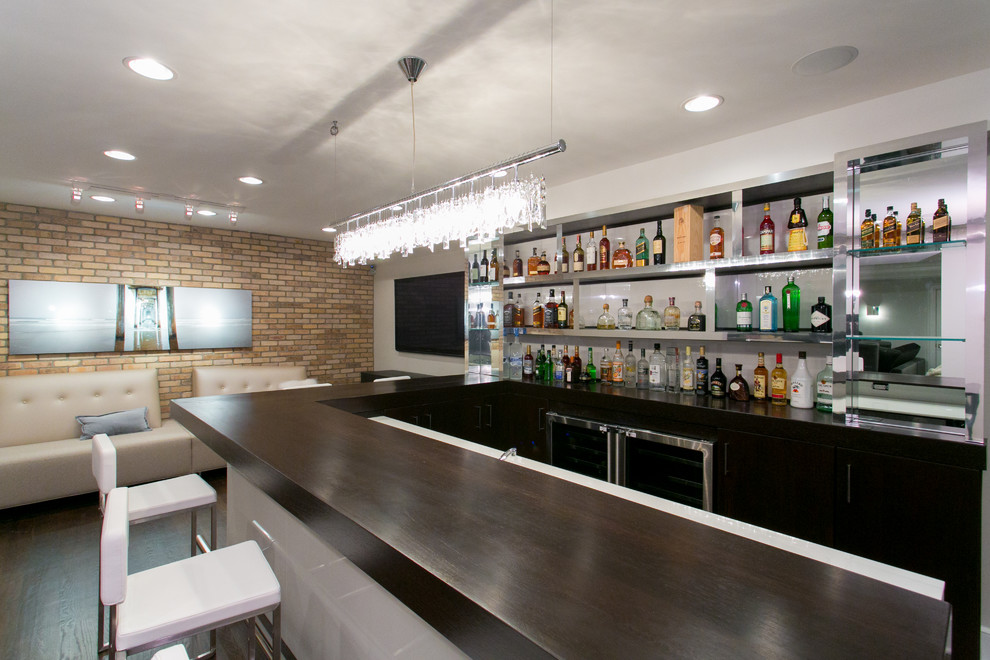 Inspiration for a large contemporary u-shaped seated home bar in New York with glass benchtops, white splashback, dark hardwood floors and black cabinets.
