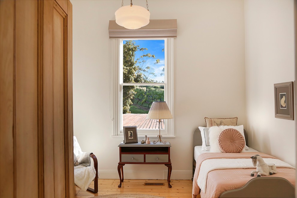 This is an example of a transitional bedroom in Geelong with white walls, medium hardwood floors and brown floor.