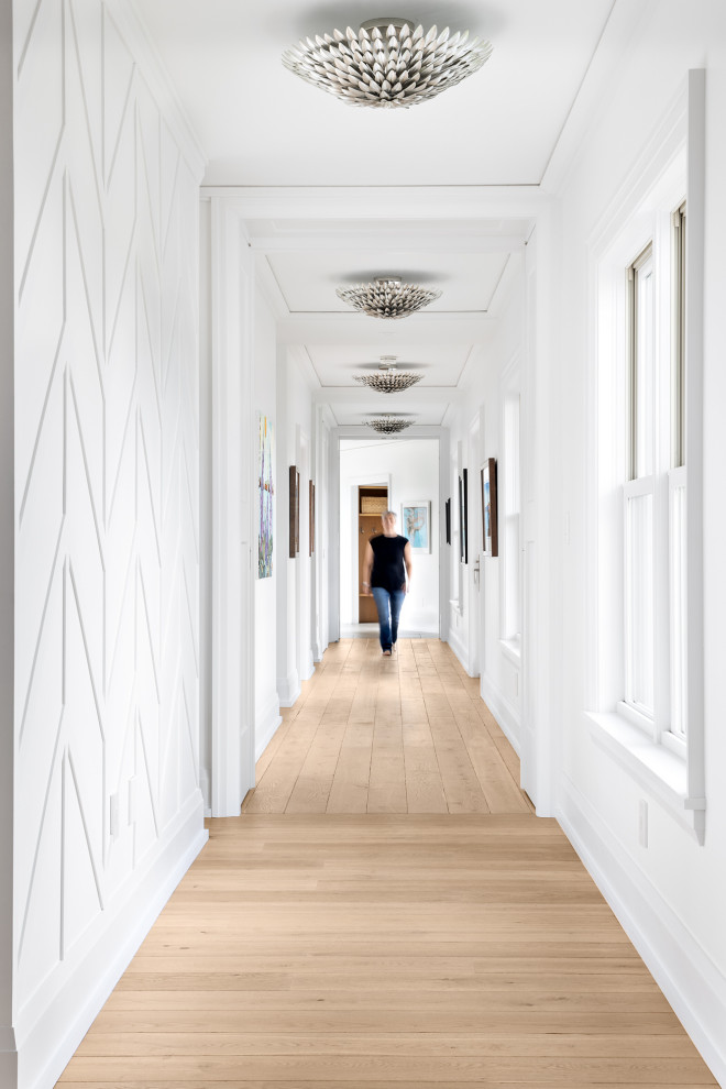 Idee per un ampio ingresso o corridoio stile marinaro con pareti bianche, pavimento marrone, pannellatura e pavimento in legno massello medio