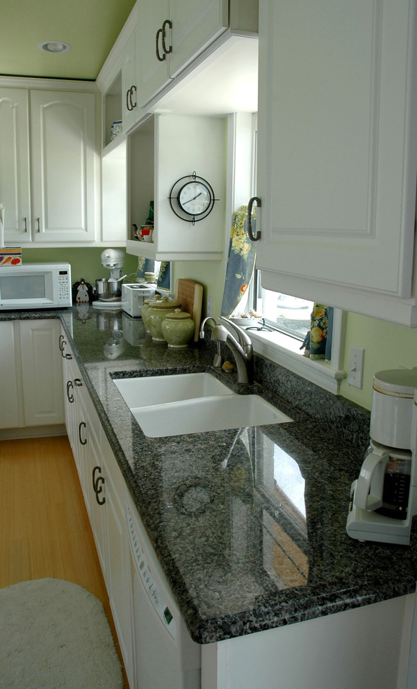 Inspiration for a large eclectic l-shaped medium tone wood floor eat-in kitchen remodel with a double-bowl sink, raised-panel cabinets, white cabinets, granite countertops, terra-cotta backsplash, white appliances and an island