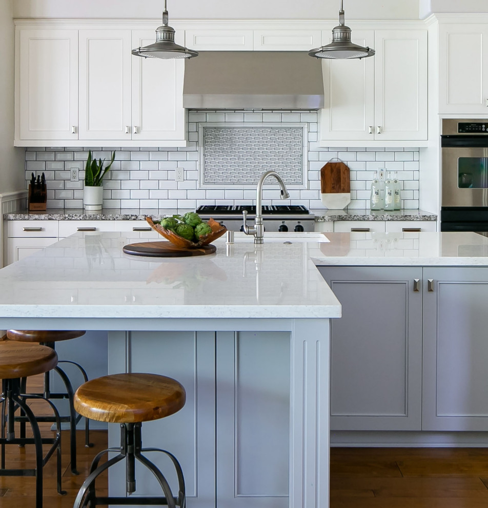 Example of a large transitional medium tone wood floor and brown floor kitchen design in Orange County with an undermount sink, shaker cabinets, gray cabinets, quartz countertops, white backsplash, subway tile backsplash, stainless steel appliances, an island and white countertops