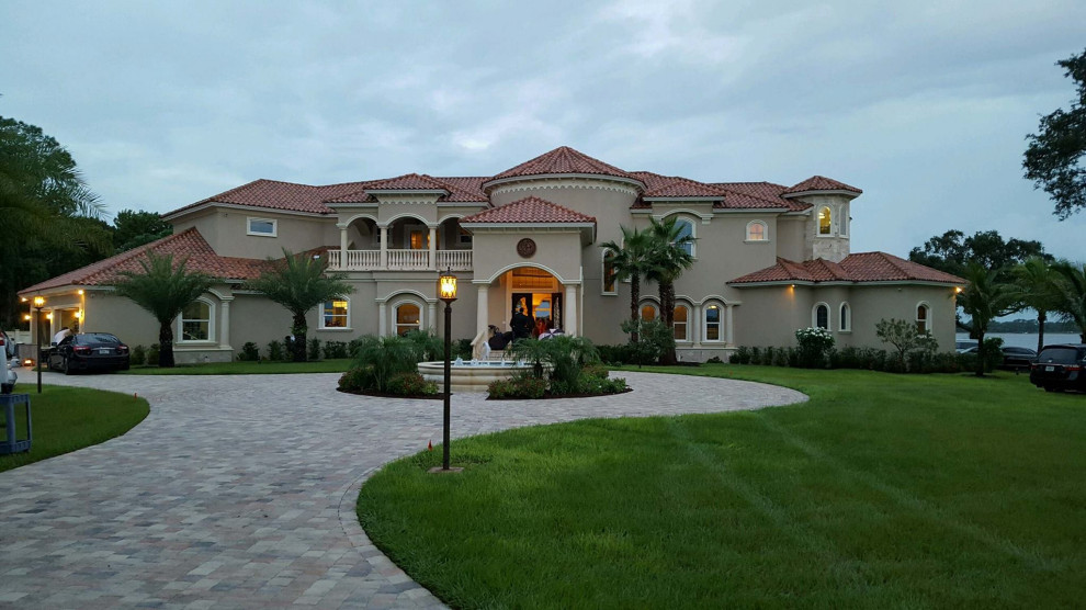 Expansive mediterranean two-storey stucco beige house exterior in Tampa with a hip roof and a tile roof.