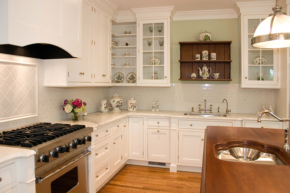 Inspiration for a large timeless l-shaped medium tone wood floor and brown floor eat-in kitchen remodel with an undermount sink, shaker cabinets, white cabinets, white backsplash, stainless steel appliances, an island and wood countertops