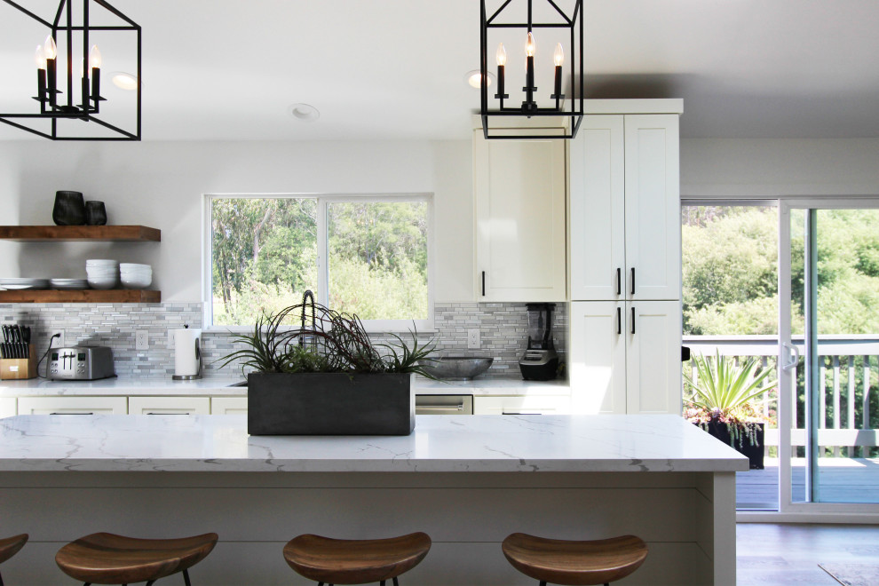 Mid-sized transitional l-shaped vinyl floor, brown floor and vaulted ceiling eat-in kitchen photo with an undermount sink, shaker cabinets, white cabinets, quartz countertops, multicolored backsplash, mosaic tile backsplash, stainless steel appliances, an island and white countertops
