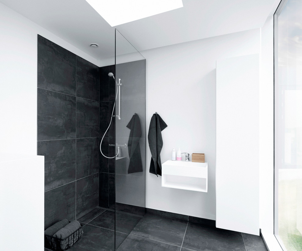 This is an example of a large scandinavian 3/4 bathroom in Copenhagen with a wall-mount sink, flat-panel cabinets, white cabinets, an open shower, black tile, stone tile, white walls, slate floors and an open shower.