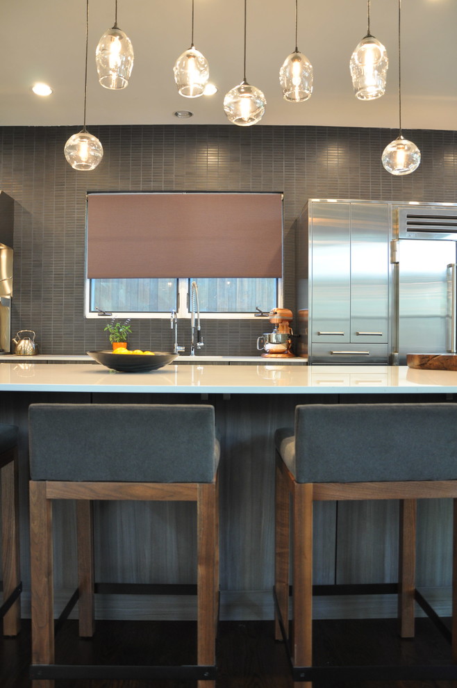 This is an example of a large contemporary open plan kitchen in Dallas with flat-panel cabinets, dark wood cabinets, quartz benchtops, black splashback, mosaic tile splashback, stainless steel appliances, with island and white benchtop.