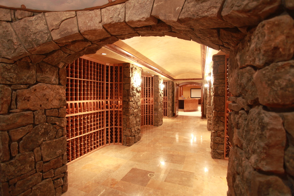 Expansive country wine cellar in Other with concrete floors, storage racks and beige floor.