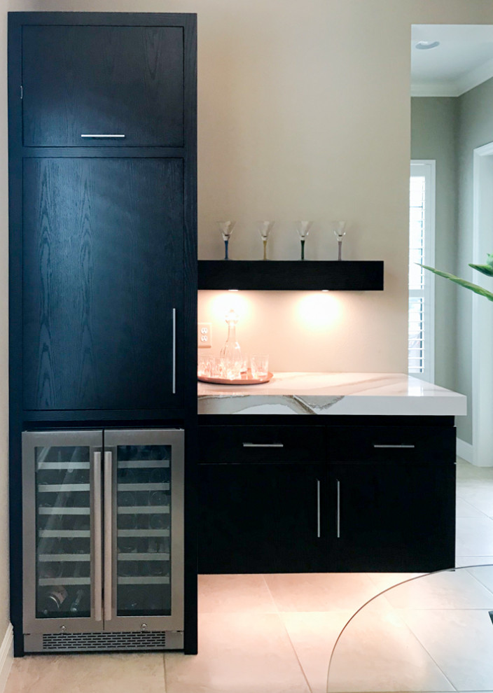 Photo of a small modern single-wall home bar in Tampa with no sink, flat-panel cabinets, black cabinets, beige floor and white benchtop.