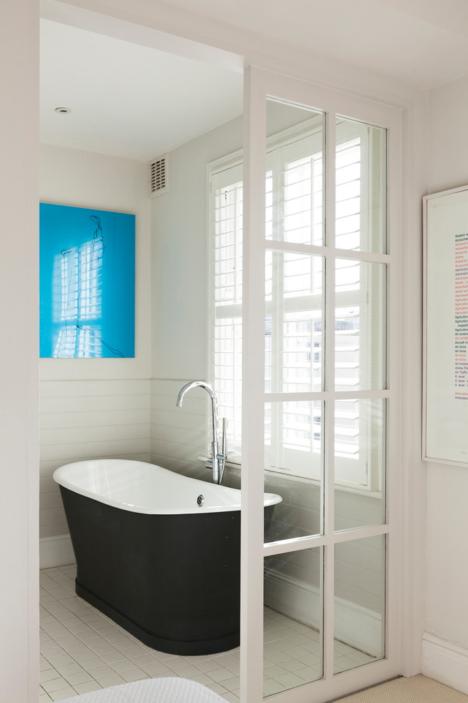 This is an example of a mid-sized scandinavian bathroom in London with a freestanding tub and white walls.