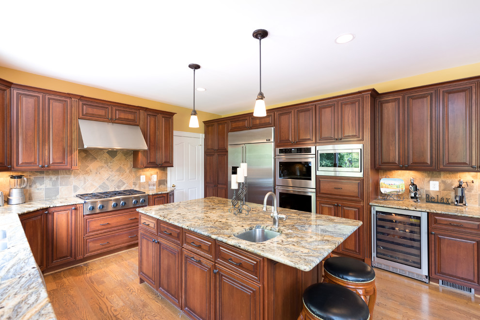 Design ideas for a mid-sized transitional u-shaped eat-in kitchen in DC Metro with an undermount sink, raised-panel cabinets, dark wood cabinets, granite benchtops, beige splashback, stone tile splashback, stainless steel appliances, medium hardwood floors and with island.