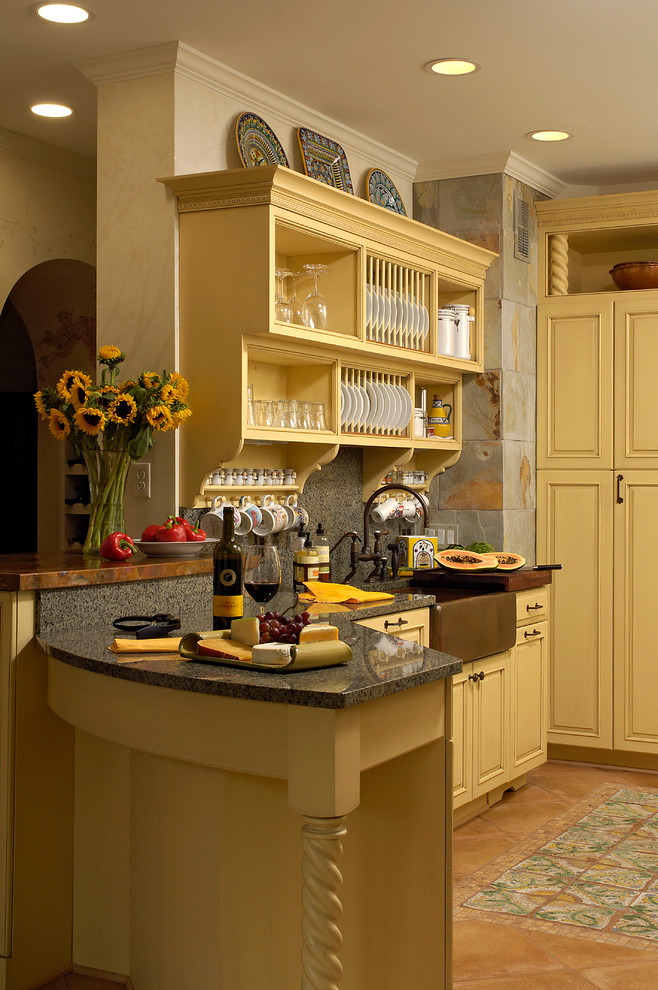 This is an example of a mid-sized traditional u-shaped kitchen pantry in DC Metro with a farmhouse sink, beaded inset cabinets, yellow cabinets, granite benchtops, grey splashback, stone tile splashback, panelled appliances, terra-cotta floors, a peninsula and beige floor.