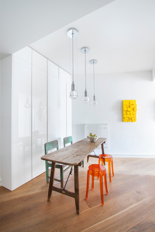 This is an example of a mid-sized contemporary separate dining room in Madrid with white walls, medium hardwood floors and no fireplace.