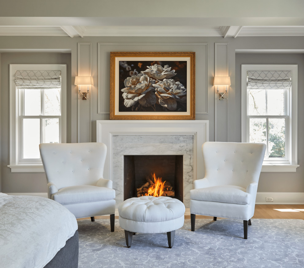 Mid-sized country master bedroom in Chicago with grey walls, light hardwood floors, a standard fireplace, a wood fireplace surround, beige floor, coffered and panelled walls.