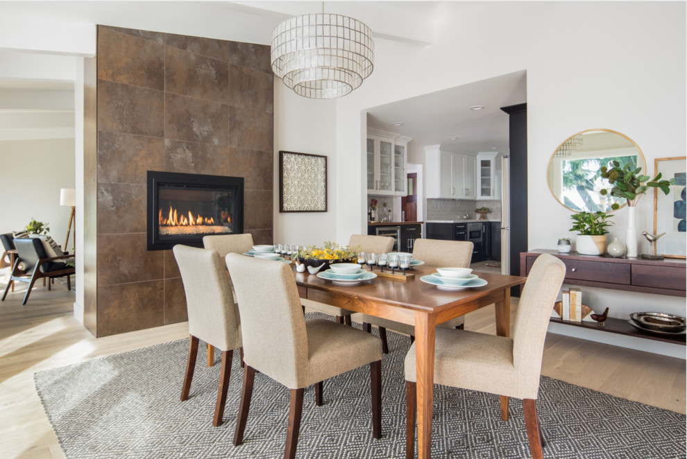 Design ideas for a transitional dining room in San Francisco with white walls, light hardwood floors, a standard fireplace and a metal fireplace surround.