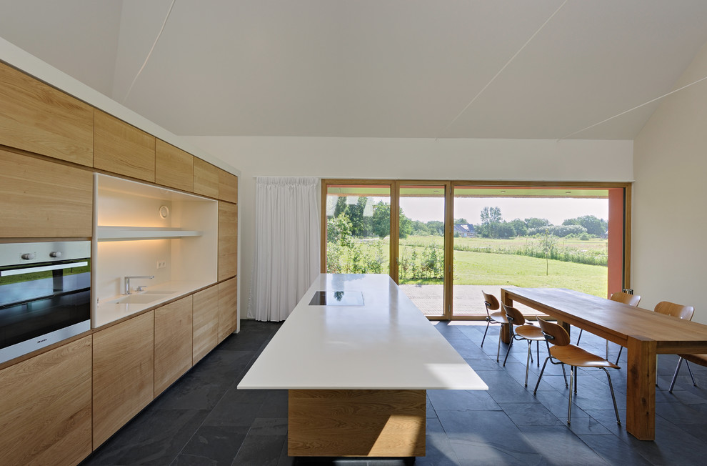 Inspiration for a large contemporary eat-in kitchen in Berlin with flat-panel cabinets, medium wood cabinets, with island, an integrated sink, white splashback, panelled appliances and slate floors.