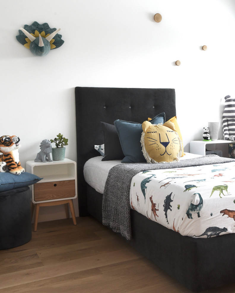 Contemporary gender-neutral kids' bedroom in Sydney with white walls, medium hardwood floors and brown floor for kids 4-10 years old.